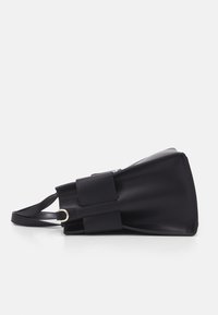 Black leather handbag featuring a structured design, flat base, adjustable strap, and two rectangular flaps on the front.