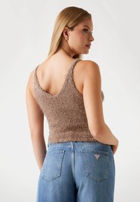 Prune pehmeast lõngast kootud tank top V-kaelusega ja tekstureeritud viimistlusega, kaasas kõrge vöökohaga helesinised teksad, millel on tagataskud ja logo detail.