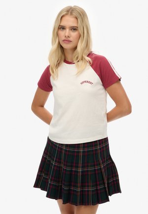 T-shirt blanche avec des manches raglan bordeaux et le logo "Superdry". Associée à une jupe plissée en tartan dans des teintes vert foncé, rouge, jaune et blanc.