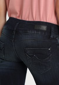 Mörkblå denimjeans med slim fit, som har en liten svart läderlapp märkta "LTB" och rundade bakfickor med sömdekor.