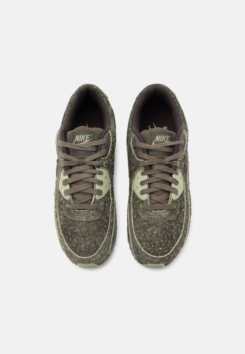 Nike sneakers featuring a textured dark green upper, light green accents, and brown laces. Rounded toe and padded collar design.