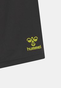 Zwarte sportshorts met een prominent groen "hummel" logo en bijenembleem op de onderlinkerkant, gemaakt van een gladde stof.