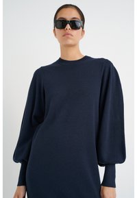 Abito in maglione blu navy con scollo rotondo e maniche lunghe e voluminose. Tessuto a maglia morbido con una texture liscia.