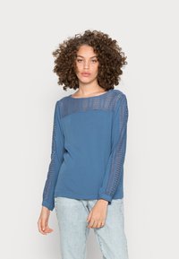 Camisola de mangas longas azul com detalhes em renda nos ombros e mangas, feita de tecido suave, com decote redondo e corte descontraído.