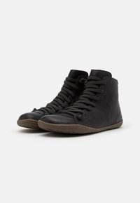 Botine negre din piele cu vârful rotund, superior texturat și talpă din cauciuc rotunjită. Prezintă șireturi verticale și un design minimalist.