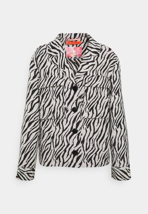 Veste à imprimé zèbre en noir et blanc, avec un col cranté, trois poches avant et des boutons noirs, confectionnée dans un tissu texturé.