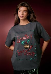 Grijs katoenen t-shirt met kleurrijke paillettenversieringen in rood, groen en goud, met decoratieve tekst en een feestelijk grafisch ontwerp.