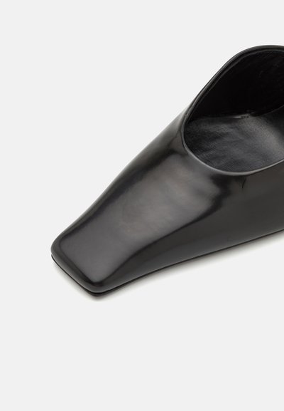 Sort lædersko med spids tå og åben hæl. Glat tekstur med en blank finish. Minimalistisk design, ingen synlig hardware eller accenter.