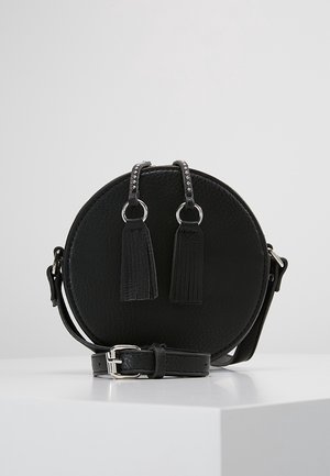 Okrągła czarna skórzana torebka na ramię z paskiem na klamrę w kolorze srebrnym oraz dwoma zamkami błyskawicznymi z chwostami, ozdobionymi srebrnymi pierścieniami i ćwiekami.