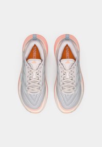 Svetlosivé atletické topánky s sieťovaným zvrškom, ružovou priesvitnou podrážkou a kontrastnou oranžovou vložkou. Sú vybavené šnúrkami a značkovými detailmi.