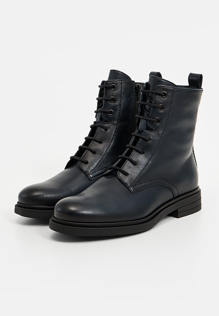 Donkerblauwe leren enkelboots met vetersluiting en een gestructureerde afwerking, voorzien van een zijrits, stevige zwarte zool en een ronde neus.