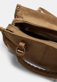 Sac à main en daim marron avec un extérieur texturé, dotée d'un compartiment zippé, d'accents en métal et d'une poignée tressée.
