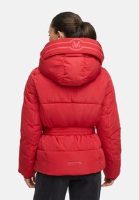 Red puffer jacket with a high collar, belted waist, and quilted texture. Features a logo patch on the collar and a smooth finish.