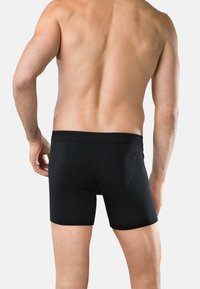Svarta boxerkalsonger med ribbad textur, med ett brett elastiskt midjeband och en figurnära passform, som bärs av en manlig modell sett bakifrån.