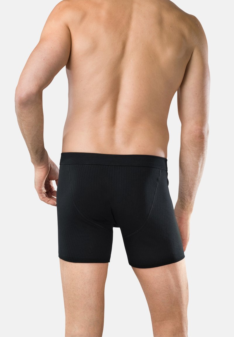 Svarta boxerkalsonger med ribbad textur, med ett brett elastiskt midjeband och en figurnära passform, som bärs av en manlig modell sett bakifrån.
