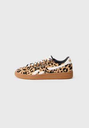 Zapatilla baja Reebok con estampado de leopardo, rayas blancas, cordones blancos y suela de goma marrón sobre un fondo liso gris claro.
