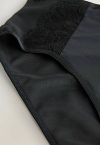 Zwarte lingerie met een gladde textuur en kantaccent. Heeft een naadloos ontwerp met een subtiele glans en ingewikkelde kantdetails aan één kant.