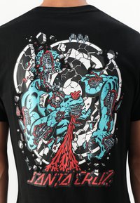 Zwarte T-shirt met een gedetailleerde afbeelding van een blauwe figuur met robotachtige elementen, rode accenten en scheurpatronen, gelabeld met "SANTA CRUZ."