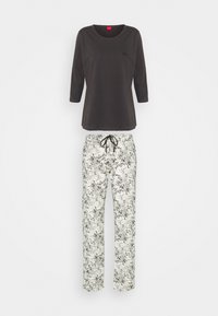 Dunkelgraues Langarmoberteil kombiniert mit weißen Hosen, die ein florales schwarzes Design aufweisen. Die Hosen haben einen Kordelzugbund und einen lockeren Schnitt.