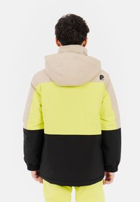 Kleurgeblokte jas met gele, beige en zwarte panelen. Gemaakt van een gladde stof met een verstelbare capuchon en elastische manchetten.