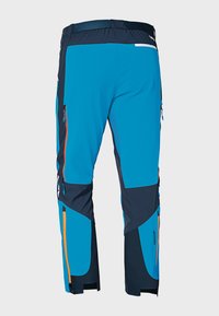 Niebieskie i granatowe spodnie techniczne z kieszeniami na zamek, elastycznym pasem i kontrastującymi pomarańczowymi akcentami. Wyposażone w wzmocnione kolana i mankiety.