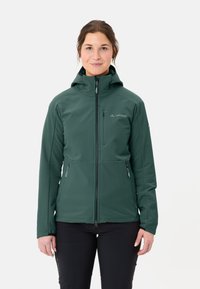 Giacca softshell verde con cappuccio, caratterizzata da una zip frontale, tasche con zip e un tessuto leggermente strutturato. Logo visibile sul petto.