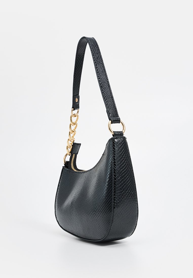 Petit sac à main en simili peau de serpent noir avec des détails en chaîne dorée et une seule bandoulière, incliné pour montrer le côté et l'avant.