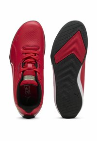 Chaussures de sport synthétiques rouges avec une texture lisse, des accents perforés, une semelle en caoutchouc noire et un design à lacets. Présente des détails de logo.