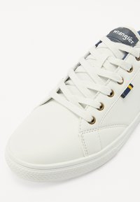 Hvite syntetiske sneakers med flate lisser, gull øyelets og en marinblå logo-lapp. Har en avrundet tå og en teksturert gummisåle.