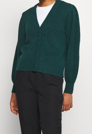 Teal gebreide cardigan met een V-hals, een zesknopen voorkant en licht pofferige lange mouwen. De textuur lijkt zacht en comfortabel met geribbelde details aan de onderkant.