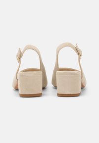 Beige semsket blokkhæl sandaler med en rygrem, der har en spænde-lukning og blød tekstur. Formet med en kontureret form og en robust, komfortabel bund.