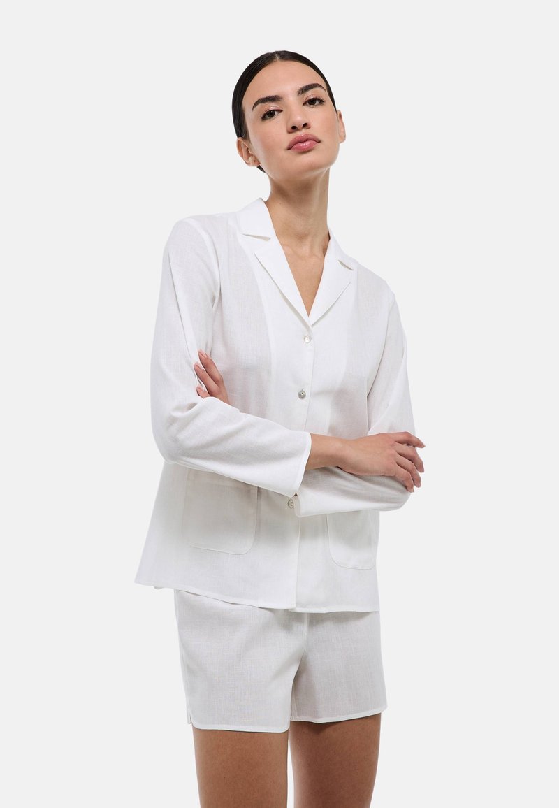 Chemise blanche en lin à manches courtes avec col revers et boutons à l'avant. Associée à un short blanc assorti, au design simple.