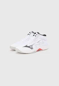 Λευκά αθλητικά παπούτσια με επάνω μέρος από δίχτυ, μαύρες λεπτομέρειες, υφή σχεδίου και κόκκινη λεπτομέρεια στη φτέρνα. Διαθέτουν εμφανές λογότυπο στο πλάι.