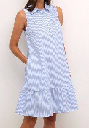 Vestido sin mangas con rayas verticales en azul claro y blanco, con cuello, botones delanteros y un dobladillo fruncido, llevado por una persona de pie.