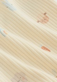 Kokvilnas audums ar krēmīgi dzeltenu ribotu tekstūru, kuru rotā gaiši zilas un brūnas dzīvnieku ilustrācijas, radot rotaļīgu rakstu.