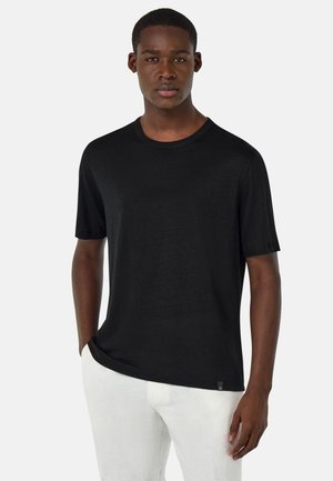 Schwarzes T-Shirt mit kurzen Ärmeln und Rundhalsausschnitt, aus einem glatten Stoff gefertigt; hat ein Etikett auf der unteren linken Seite.