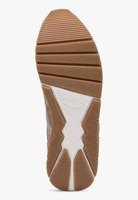 Sål af sko med en struktureret gummibund i brun, der har horisontale riller og et karakteristisk zigzag-mønster i hvid langs midten.