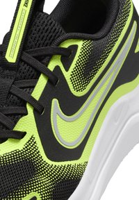 Black and neon green Nike Cosmic Runner shoe features mesh upper, reflective accents, prominent logo, and textured detailing on the sides.
