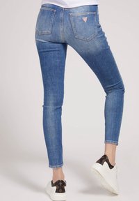 Vaqueros skinny de mezclilla, con una cintura de talle medio, bolsillos traseros y un pequeño logotipo en forma de triángulo en el bolsillo derecho.