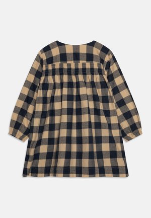 Beżowo-czarna sukienka w kratę z długim rękawem, z marszczonym nadrukiem na całych plecach oraz elastycznymi mankietami.