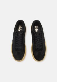 Schwarze Wildledersneaker mit texturiertem Finish, ausgestattet mit einer Gummisohle, schwarzen Schnürsenkeln und einer markierten Innensohle. Klassisches sportliches Design.