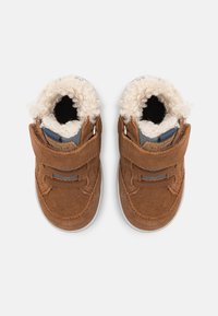 Bottes en daim marron pour tout-petits avec doublure crémeuse moelleuse, sangle Velcro et semelle en caoutchouc grise. Comprend un col rembourré pour le confort.