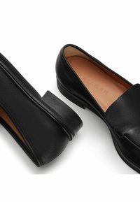 Czarne skórzane lordsy z płaskim obcasem, gładką fakturą, minimalistycznym designem i wytłoczonym logo marki na wkładce.