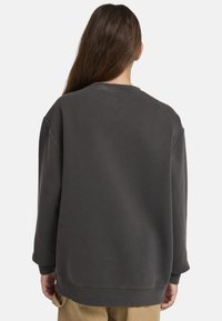 Mörkgrå sweatshirt med avslappnad passform, som har rund hals, ribbad mudd och en mjuk textur. Baksidan är enkel utan några mönster.