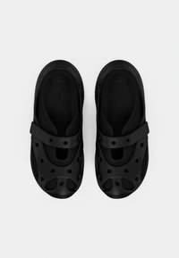 Sabots Crocs noirs avec design perforé, bride de soutien, semelle intérieure texturée et bout arrondi. Fabriqués en matériau léger.