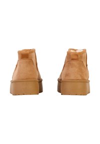 Bottes cheville en daim beige avec intérieur doux, bout rond et semelle en caoutchouc épaisse. Elles disposent d'un petit talon et d'une languette arrière pour un enfilage facile.