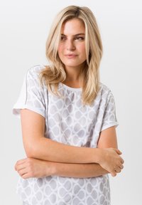 Witte kortebloemige top met een geometrisch cirkelpatroon, gemaakt van lichtgewicht materiaal met een ontspannende pasvorm en ronde halslijn.