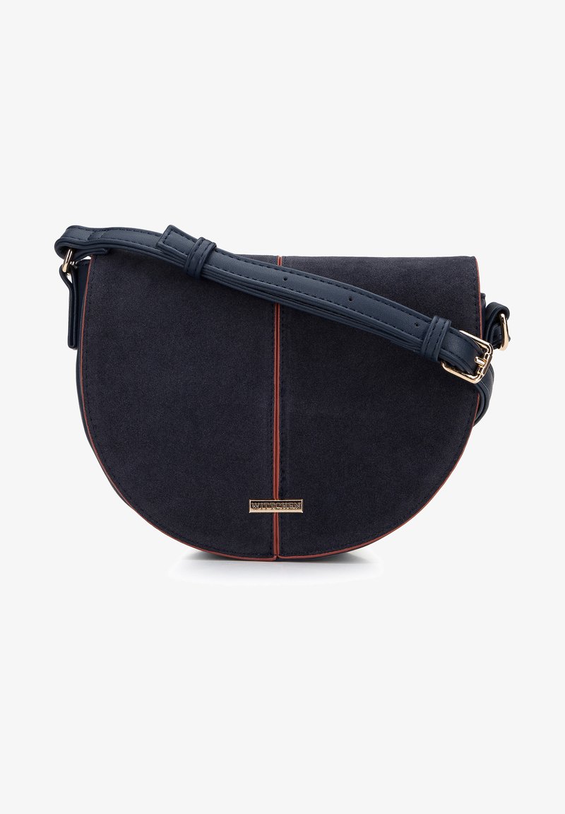 Granatowa torebka typu crossbody z zamszu o zaokrąglonym kształcie, skórzanym paskiem i kontrastującymi czerwonymi przeszyciami. Z przodu znajduje się złota płytka z logo.