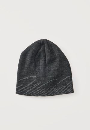 Gorro de punto gris oscuro con un sutil patrón abstracto de ondas en gris más claro cerca del borde inferior sobre un fondo liso y claro.