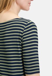 Bluzka w paski z granatową bazą i jasnoniebieskimi poziomymi paskami, okrągły dekolt i trzy czwarte rękawy. Miękki, elastyczny materiał.